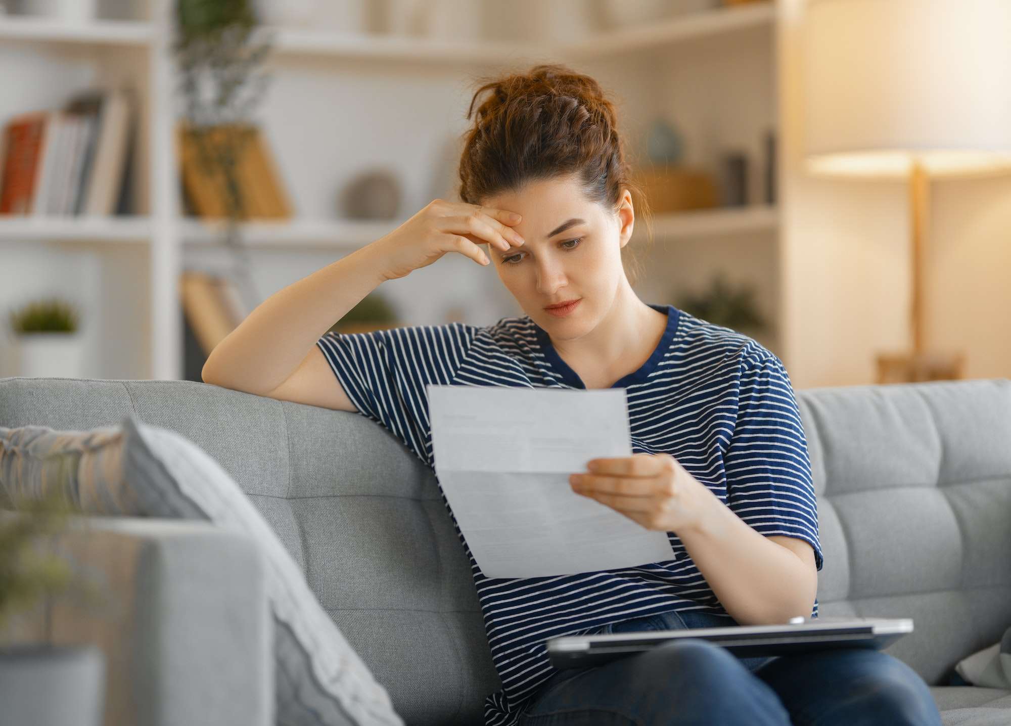 Woman, sitting on the sofa with a paper receipt