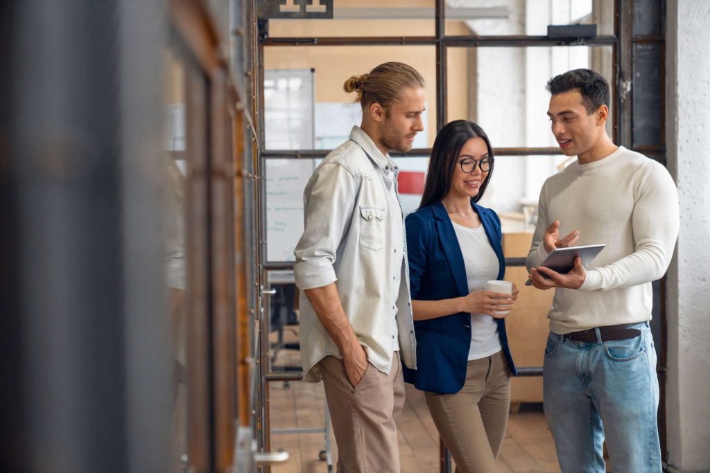 Three young business professionals standing together and discussing over business report