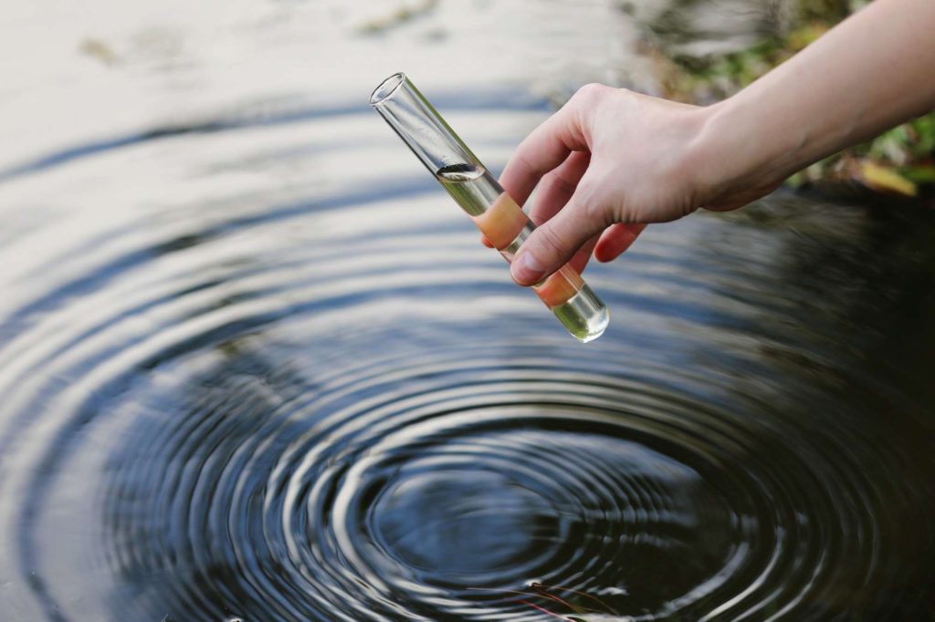 Water sample. Hand collects water to explore. Concept - water purity analysis, environment, ecology.